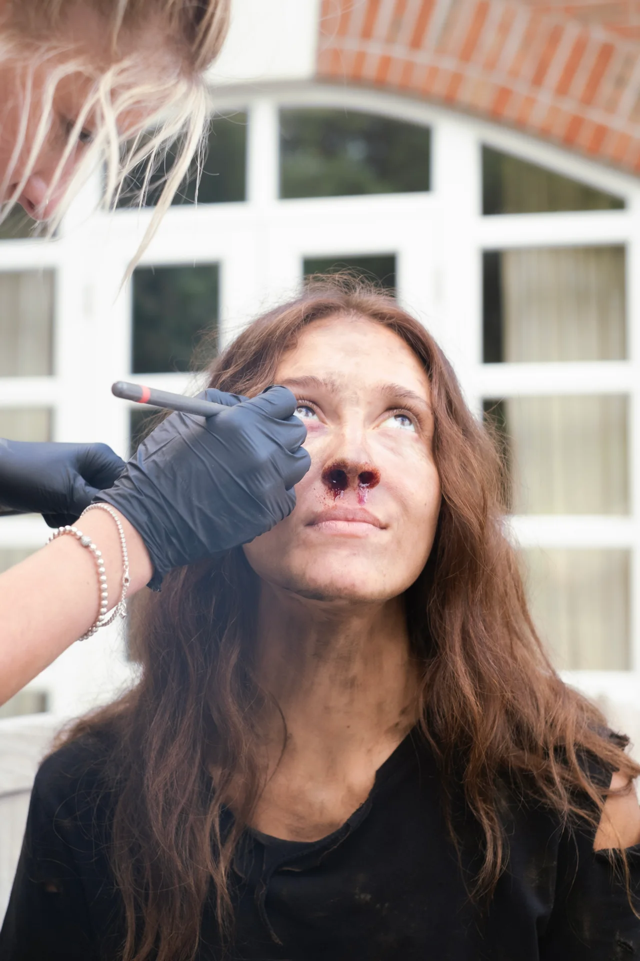A makeup artist applying the finishing touches to Kaylee McGregor's face