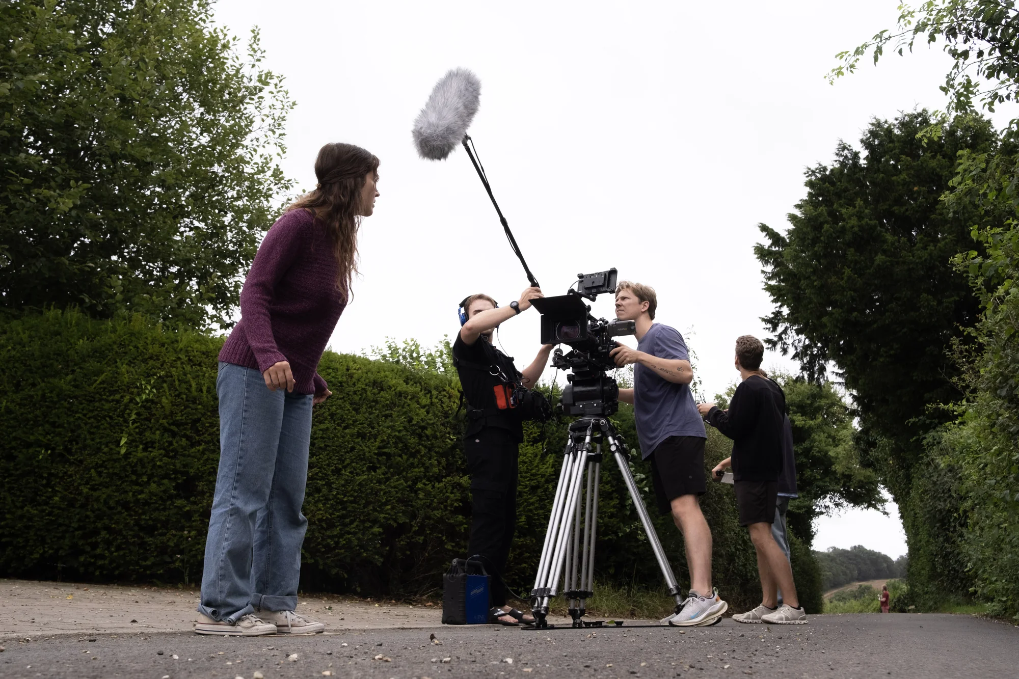 Kaylee McGregor in a purple jumper beside a camera and boom on a country road