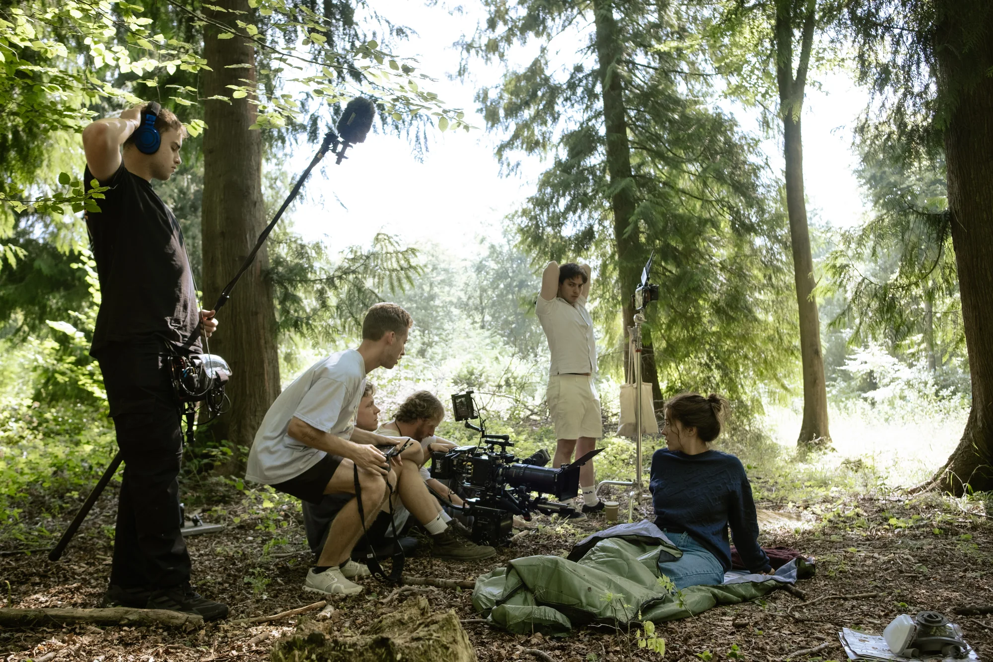 Kaylee McGregor seated on the forest floor beside the camera crew